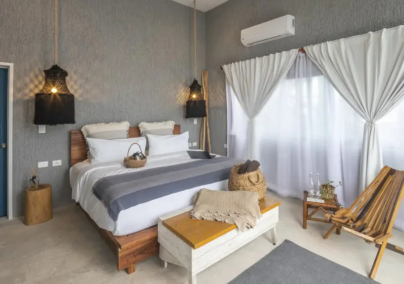 Une chambre lumineuse avec un grand lit et un fauteuil en bois.