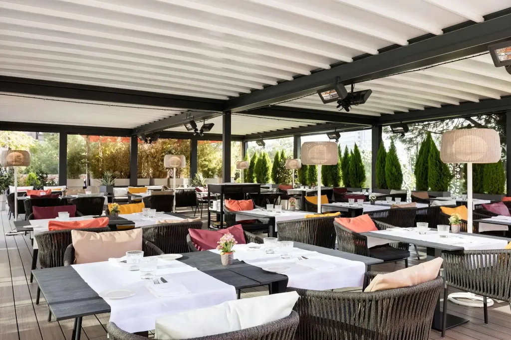 Une terrasse couverte avec des tables dressées pour un repas.