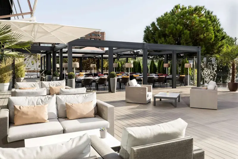 Espace de détente extérieur avec canapés et tables basses sous une pergola.