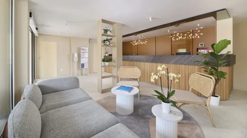 Un espace d'accueil lumineux avec des canapés et un comptoir.