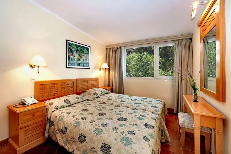 Une chambre lumineuse avec un grand lit et une coiffeuse en bois.