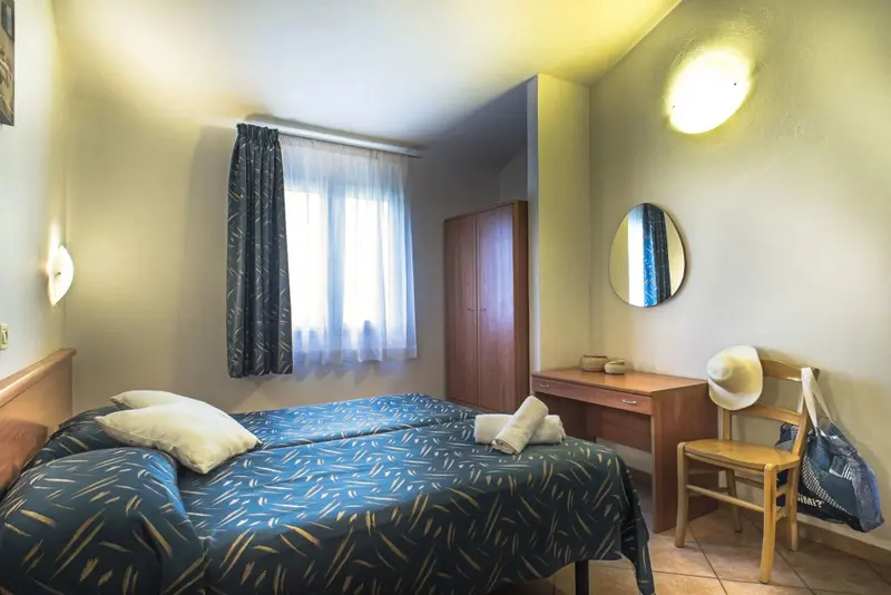 Une chambre lumineuse avec un lit double et un bureau.