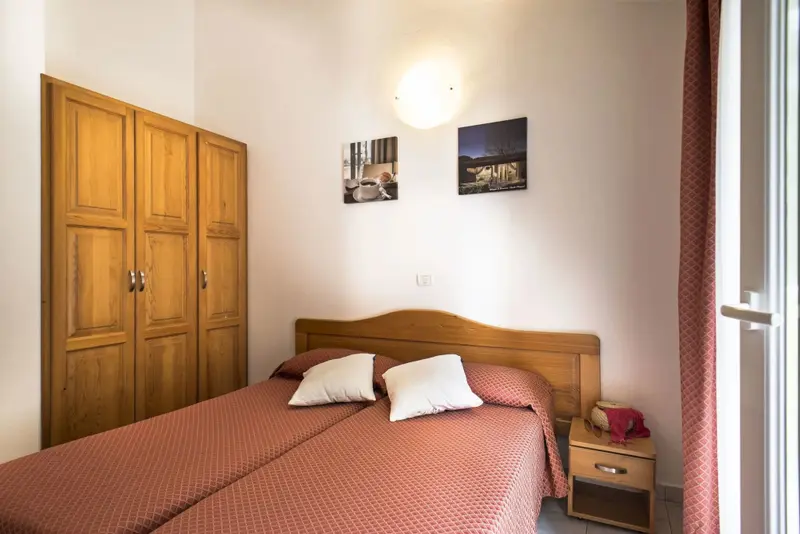 Une chambre lumineuse avec un lit double et une armoire en bois.