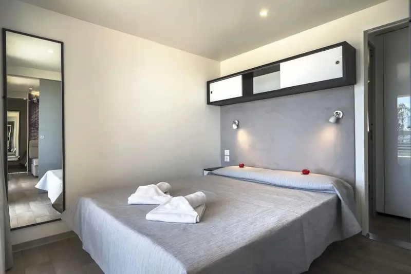 Une chambre lumineuse avec un grand lit et un miroir mural.
