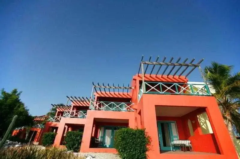 Bâtiments colorés avec des terrasses ombragées et une végétation luxuriante.