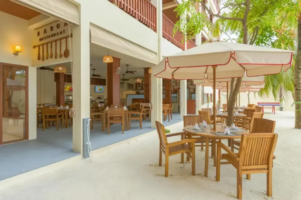 Tables et chaises disposées sur une terrasse ombragée près d'un restaurant.