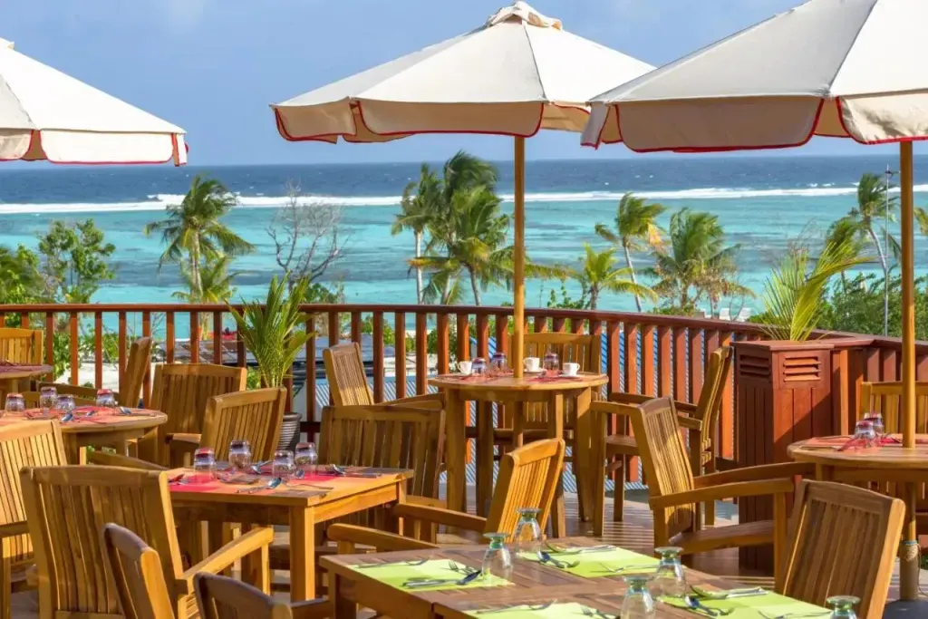 Terrasse avec tables et parasols donnant sur une mer turquoise.