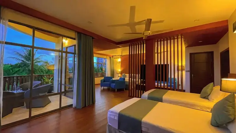 Une chambre lumineuse avec deux lits et un espace salon ouvert sur une terrasse.
