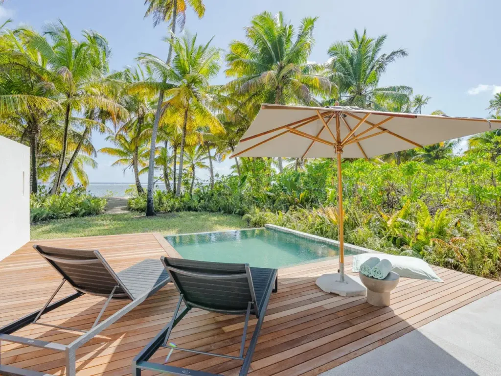 Terrasse en bois avec transats et petite piscine.