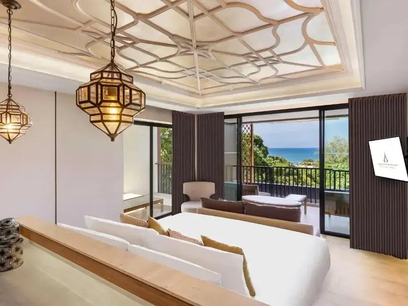 Une chambre lumineuse avec un lit et un espace détente donnant sur une vue mer.
