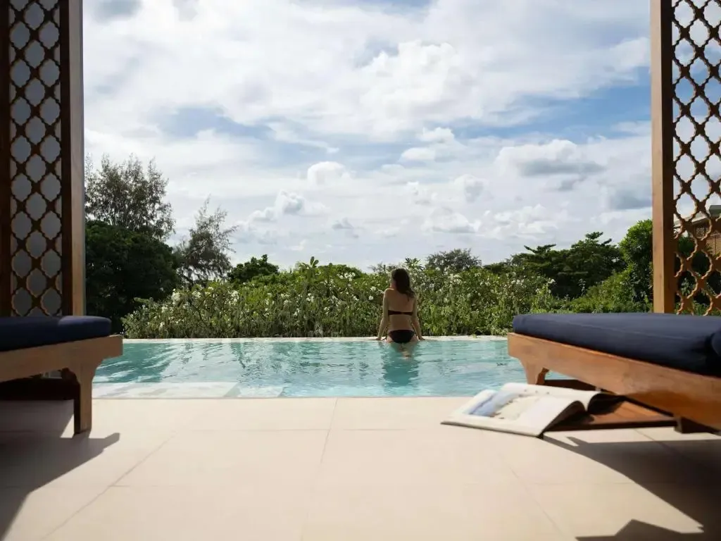 Une personne se détend dans une piscine bordée de végétation luxuriante.