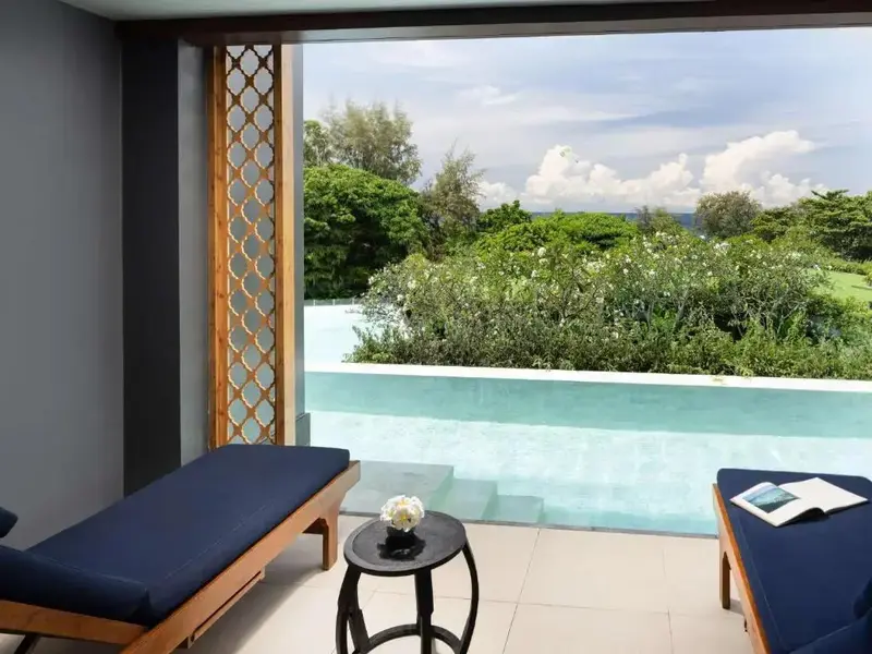 Terrasse avec transats donnant sur une piscine et une végétation luxuriante.