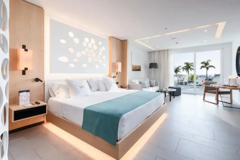 Une chambre lumineuse avec un grand lit et un accès à une terrasse.