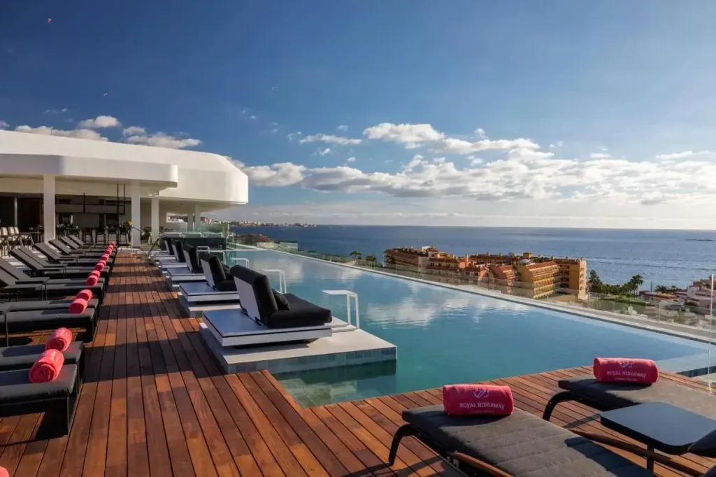 Transats alignés au bord d'une piscine à débordement avec vue sur la mer.