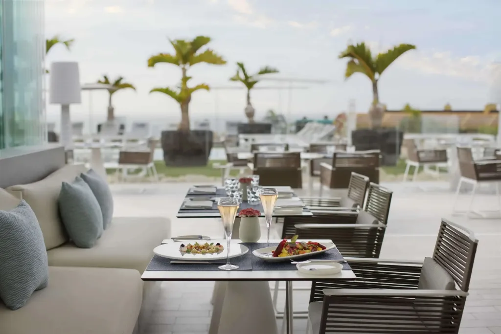 Une table est dressée avec des plats et des boissons sur une terrasse ensoleillée.