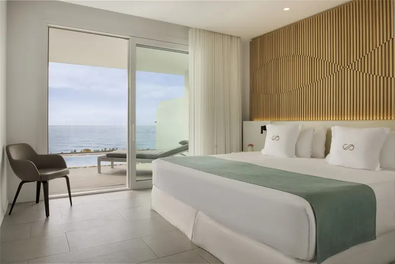 Une chambre lumineuse avec un grand lit donnant sur la mer.