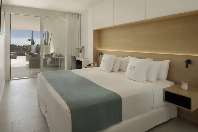 Une chambre lumineuse avec un grand lit et un accès à une terrasse.