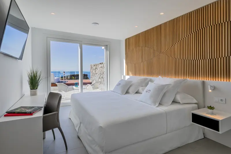 Chambre lumineuse avec un grand lit et vue sur la mer.