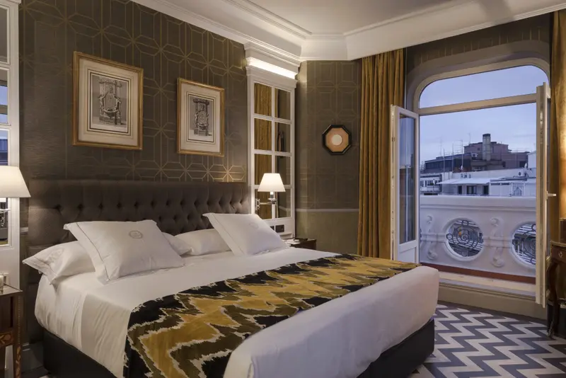 Une chambre avec un grand lit et une vue sur la ville par une baie vitrée.
