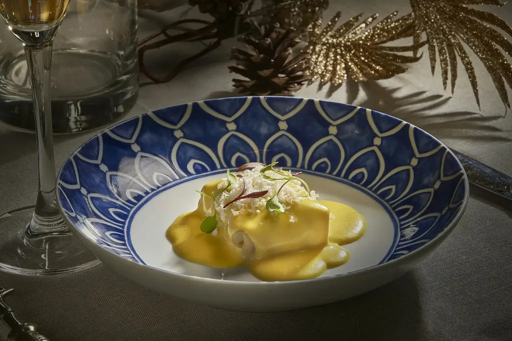 Assiette de cuisine raffinée avec une sauce jaune et des éléments décoratifs.