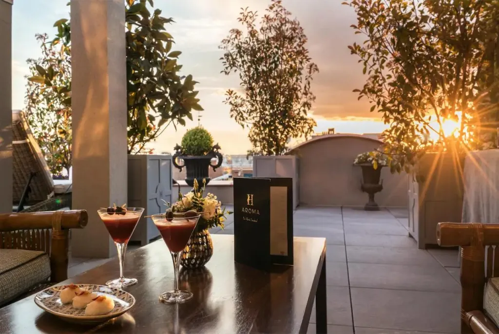 Une table de terrasse accueillant des cocktails et des amuse-gueules au coucher du soleil.