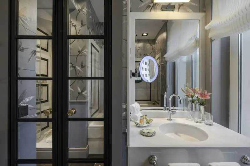 Une salle de bain lumineuse avec une baignoire visible à travers une porte vitrée.