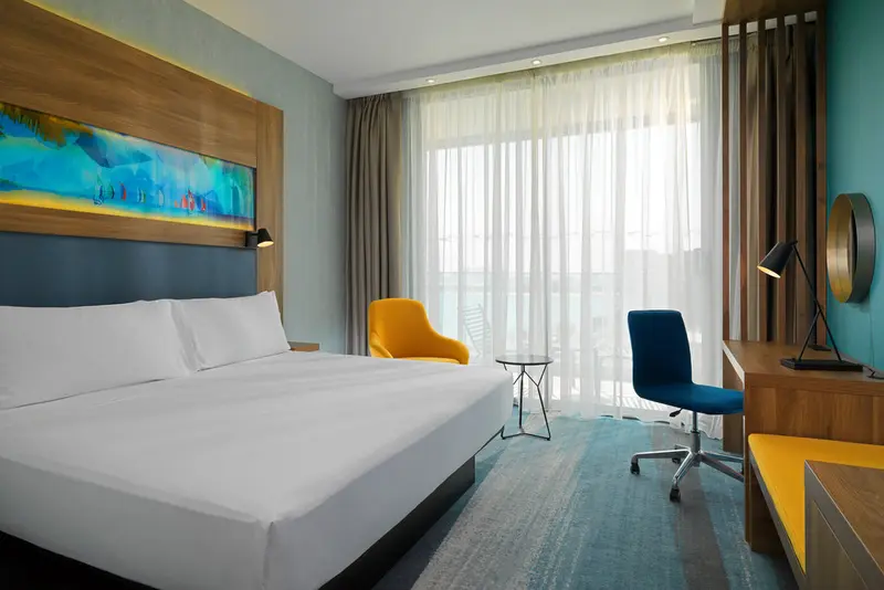 Une chambre lumineuse avec un grand lit et un espace bureau.