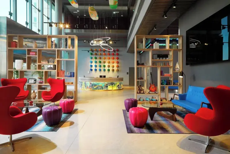 Un hall d'accueil moderne avec des fauteuils colorés et un comptoir d'enregistrement illuminé.