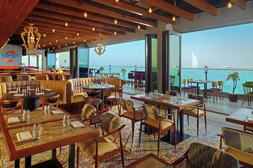 Une salle à manger lumineuse avec de grandes baies vitrées donnant sur la mer.