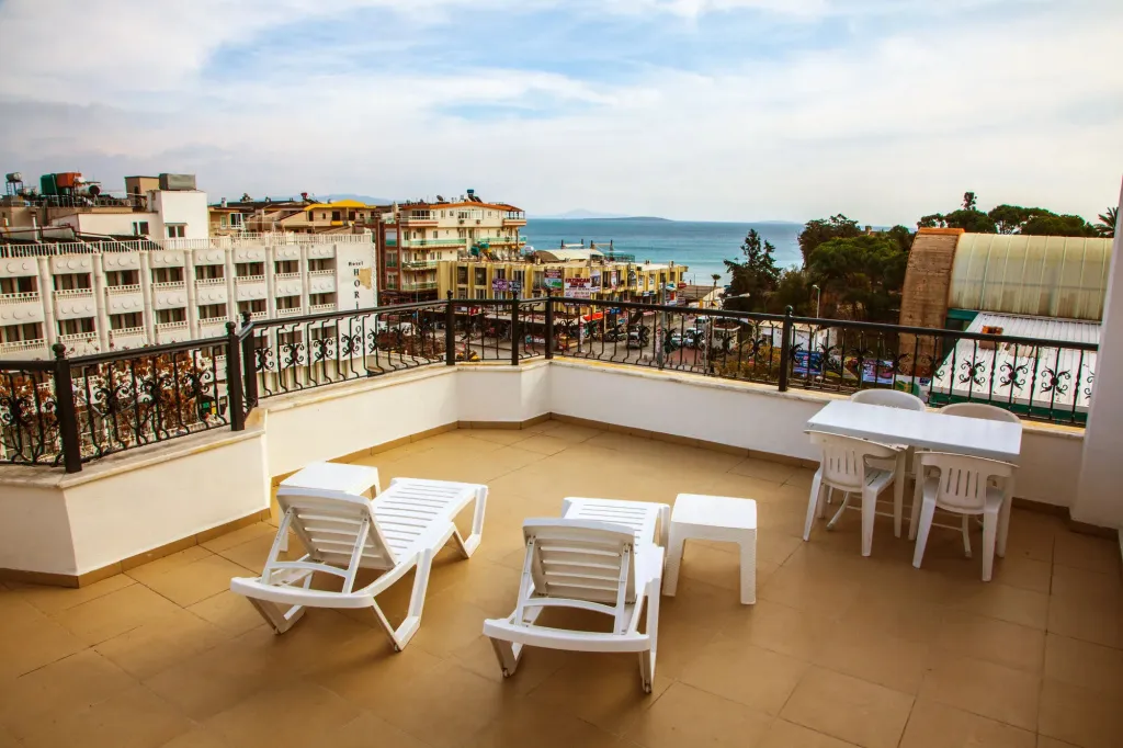 Terrasse aménagée avec chaises longues et table donnant sur une ville côtière.