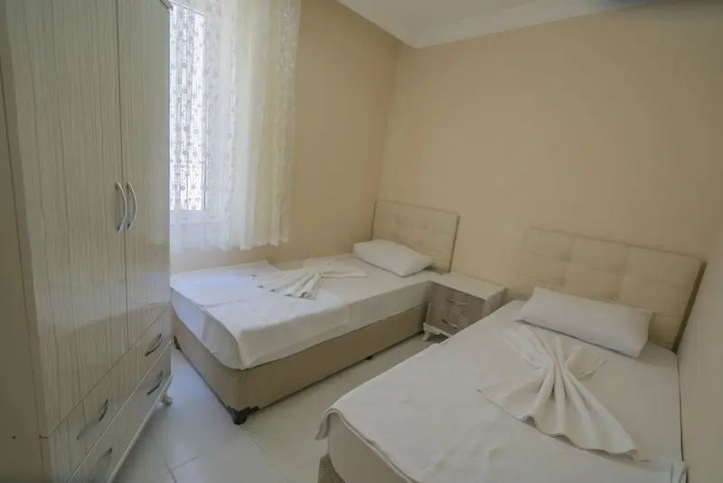 Une chambre lumineuse avec deux lits simples et une armoire.