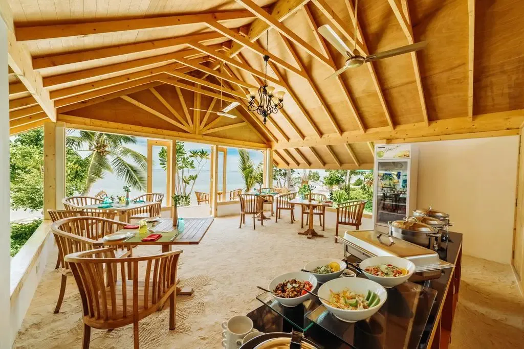 Une salle à manger lumineuse s'ouvre sur une plage de sable blanc.