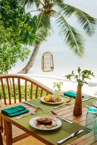Une table est dressée avec des plats colorés en extérieur, face à la mer.