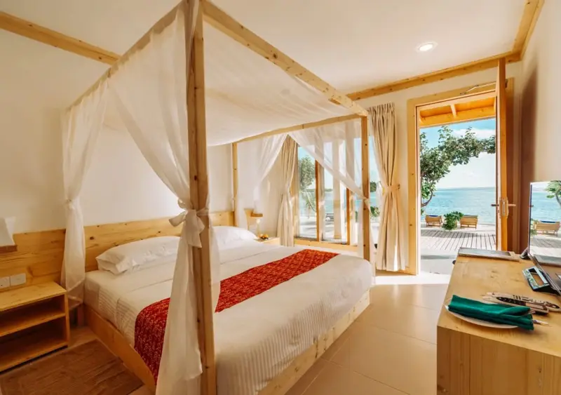 Une chambre lumineuse avec un lit à baldaquin donnant sur l'océan.
