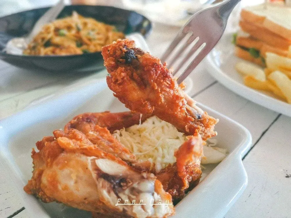 Un morceau de poulet frit est levé par une fourchette au-dessus d'une assiette.