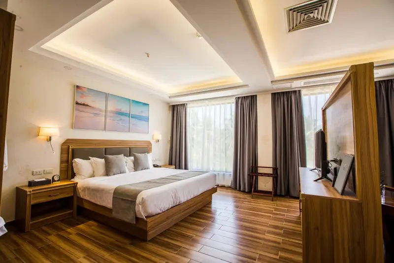 Une chambre lumineuse avec un grand lit et des tableaux décoratifs.