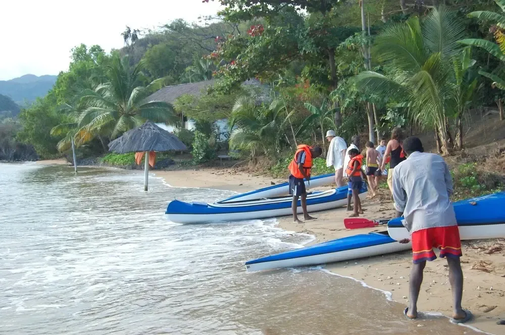 Des personnes se préparent à mettre à l'eau des kayaks sur une plage de sable.