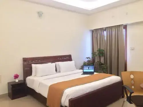 Une chambre lumineuse avec un lit double et un ordinateur portable.