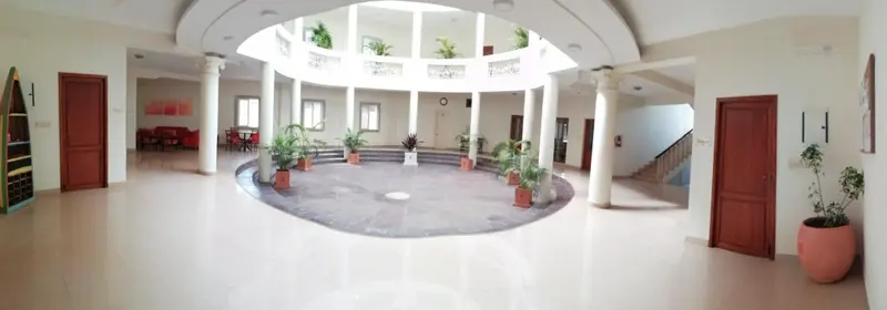 Vaste hall d'entrée circulaire avec colonnes et plantes.