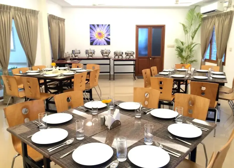 Une salle lumineuse avec des tables dressées pour un repas.