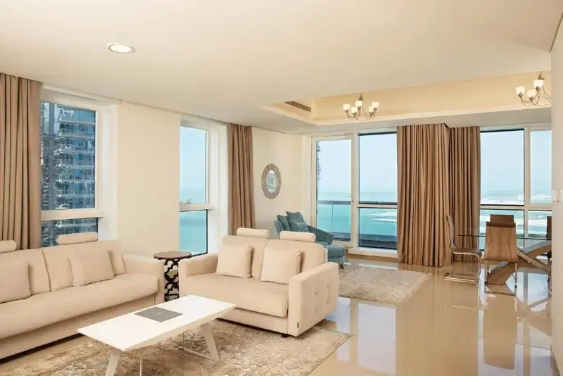 Un salon lumineux avec canapés et table basse offre une vue sur la mer.