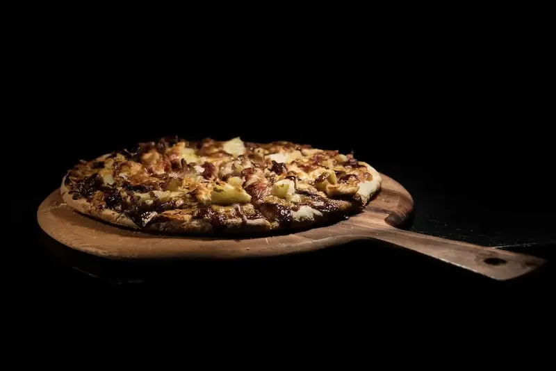 Une pizza généreusement garnie est présentée sur une planche en bois.