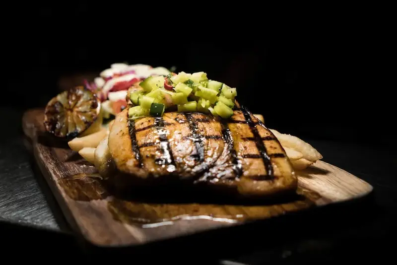 Assiette de poisson grillé accompagnée de frites et d'une sauce fraîche.