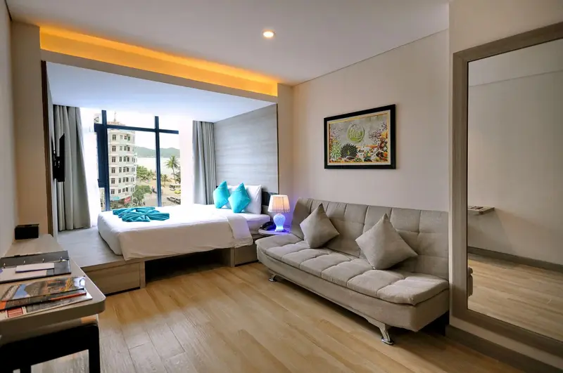 Une chambre lumineuse avec un lit et un canapé près d'une grande fenêtre.