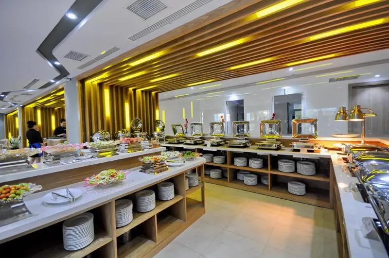 Un buffet propose une grande variété de plats et de salades dans une salle lumineuse.