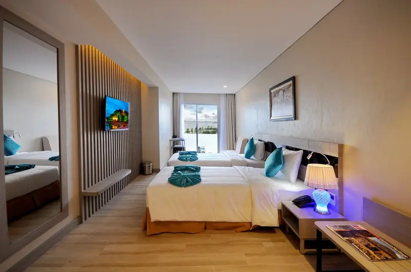 Une chambre lumineuse avec deux lits et une vue sur la mer.