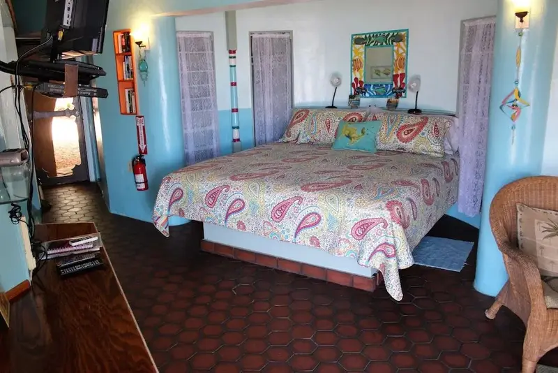 Une chambre lumineuse avec un grand lit recouvert d'une courtepointe colorée.