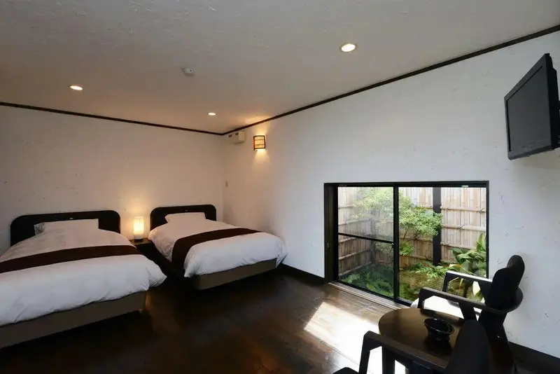 Une chambre lumineuse avec deux lits et une vue sur un jardin.