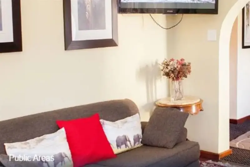 Un canapé gris avec des coussins colorés est placé devant un mur beige orné de tableaux.