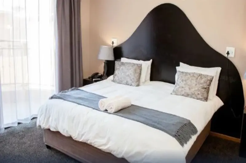 Une chambre lumineuse avec un grand lit recouvert d'une courtepointe et de coussins.